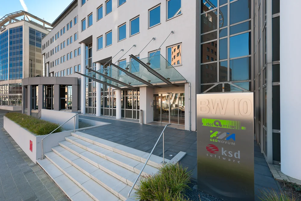 Voorzijde van een modern kantoorgebouw aan de Barchman Wuytierslaan met een bord waarop de namen van gevestigde bedrijven staan.